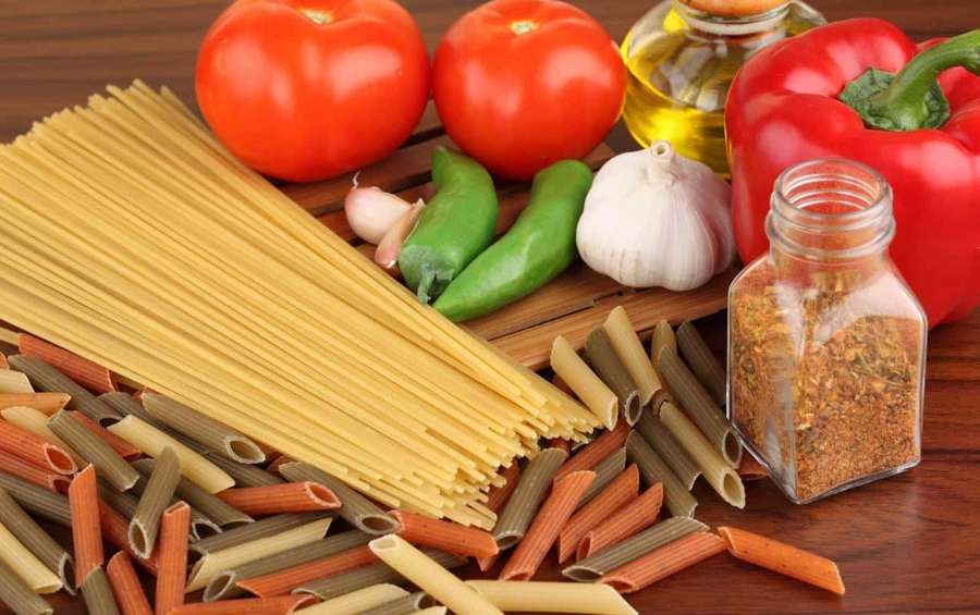 Frische Pasta-Zutaten wie Tomaten, Paprika, Knoblauch und Gewürze auf einem Holzbrett. — Pasta Bilder
