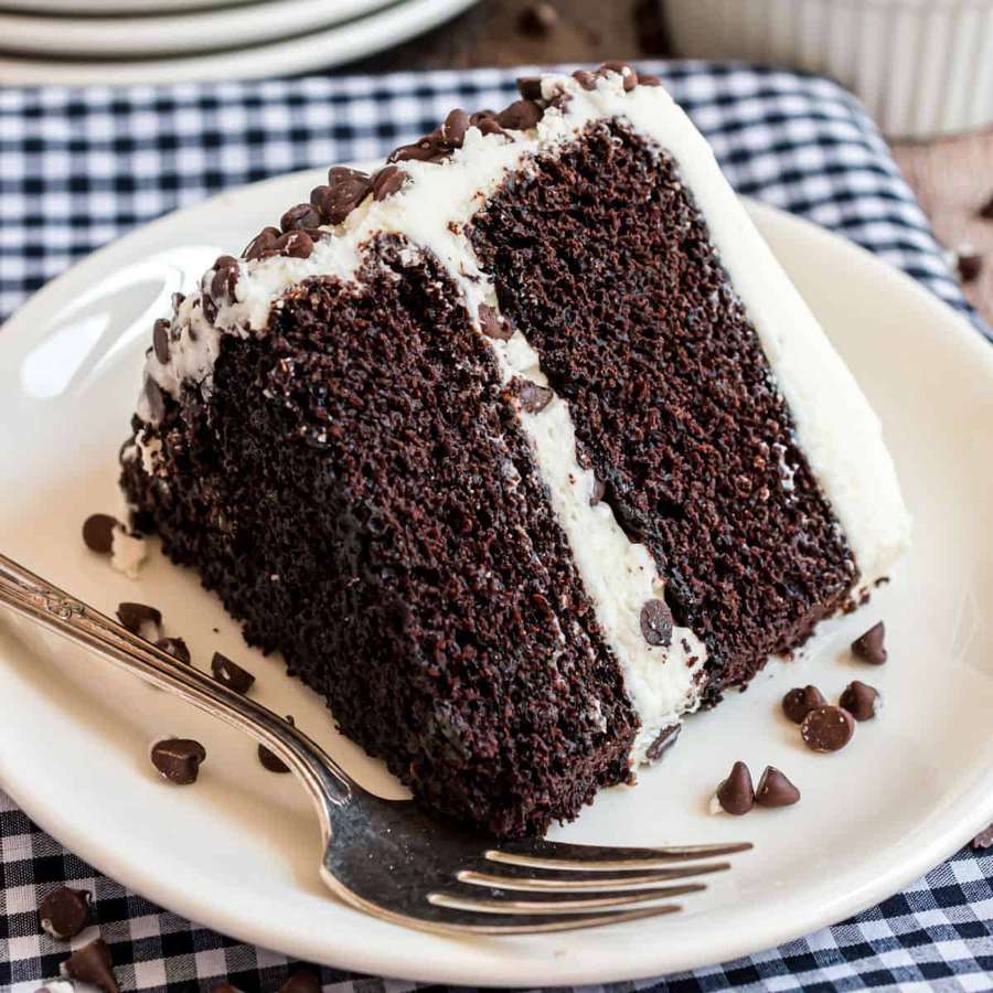 Rebanada de pastel de chocolate con glaseado blanco y chispas de chocolate sobre un plato. — Pastel de chocolate Fondos de pantalla