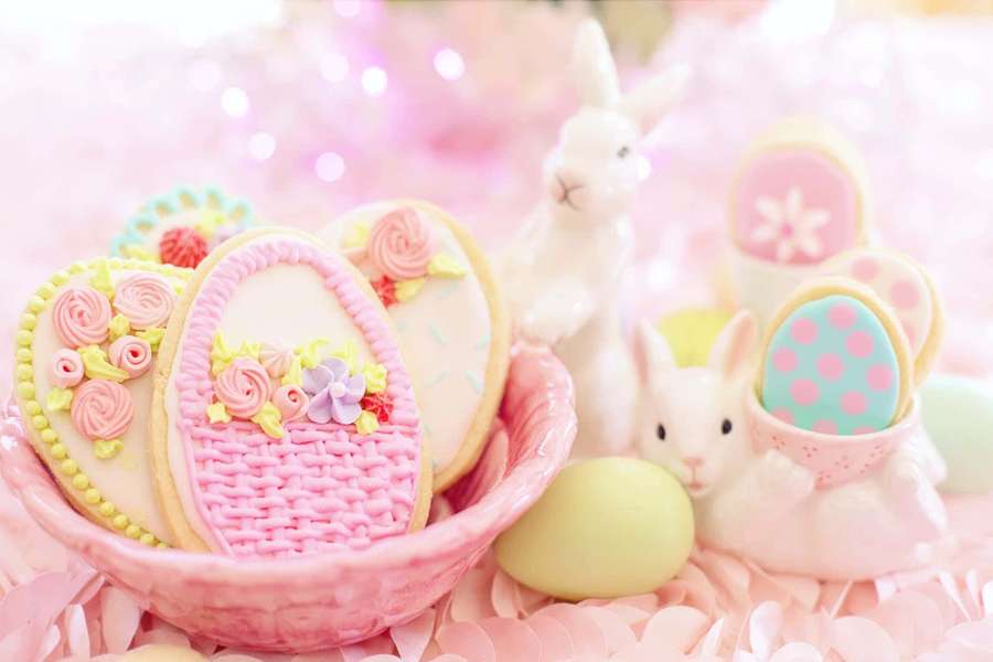 Easter cookies and bunnies in pastel colors on a pink petal background. — Pastel Easter Wallpaper