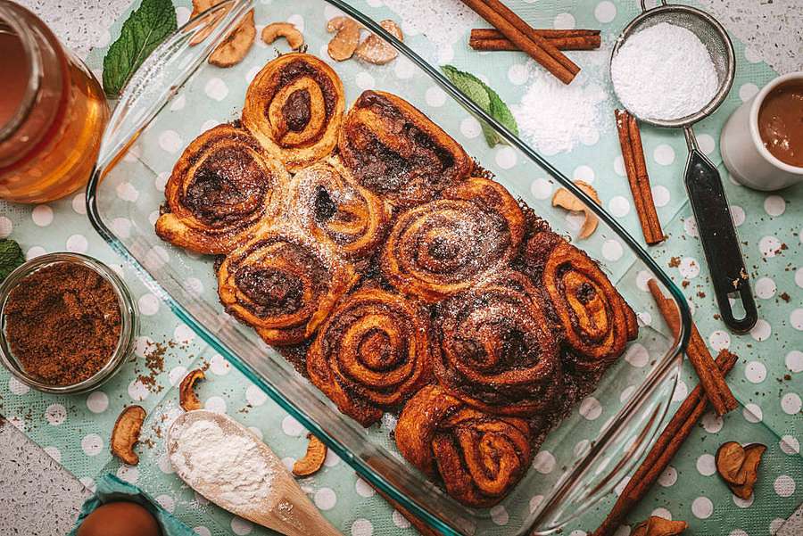 Rollos de canela frescos en fuente de vidrio con ramas de canela y azúcar alrededor. — Pasteles Fondos de pantalla