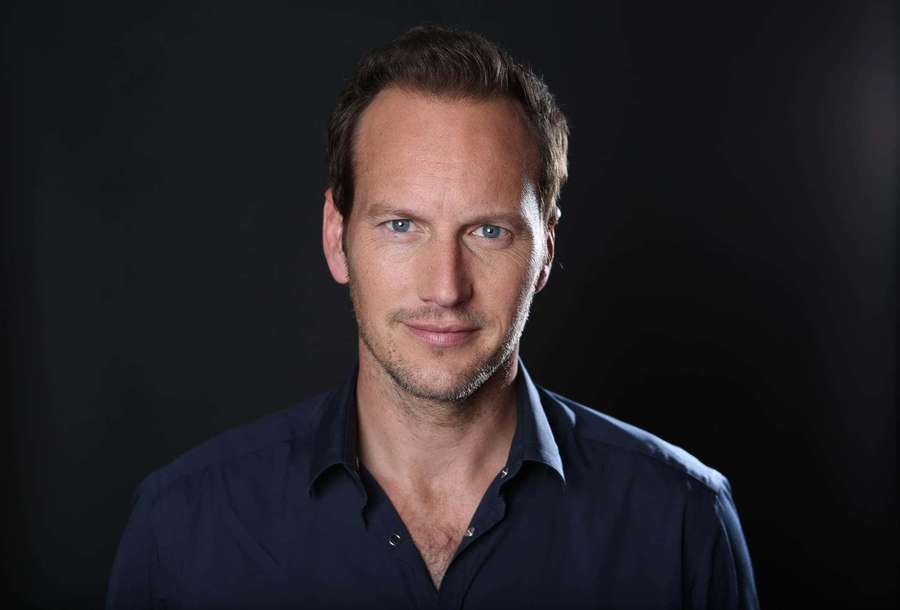 A man in a dark blue shirt looks directly at the camera in a studio portrait. — Patrick Wilson Wallpaper