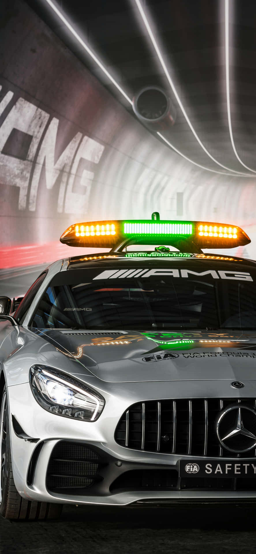 Silverfärgad Mercedes-AMG säkerhetsbil med blinkande ljus i en tunnel. — Beskyddare bakgrund Bakgrundsbilder