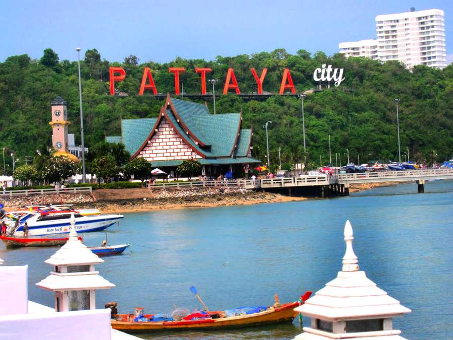 Pattaya city sign overlooking a harbor with boats and a Thai-style building. — Pattaya Wallpaper