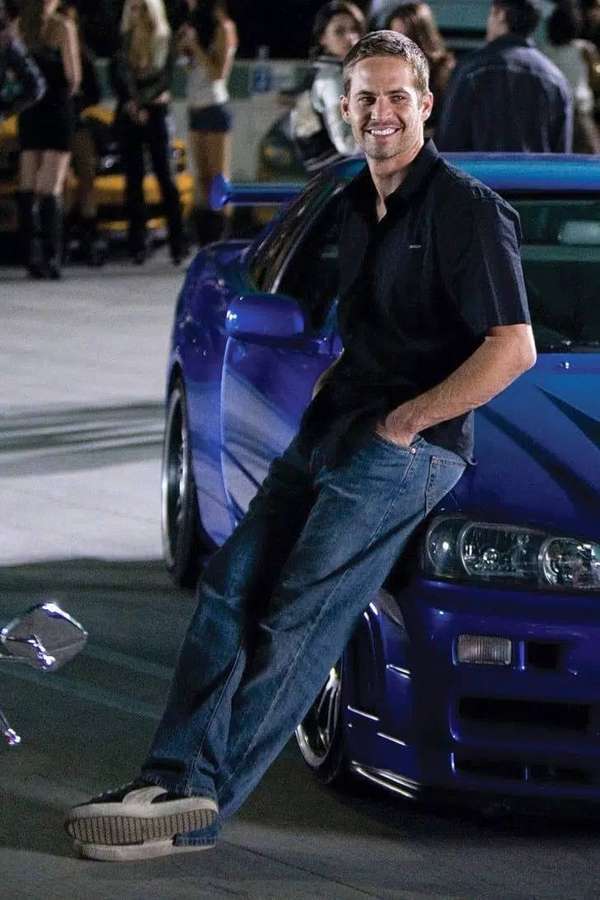 Mann in Jeans lehnt nachts an blauem Sportwagen mit Menschenmenge dahinter. — Paul Walker Auto Wallpaper