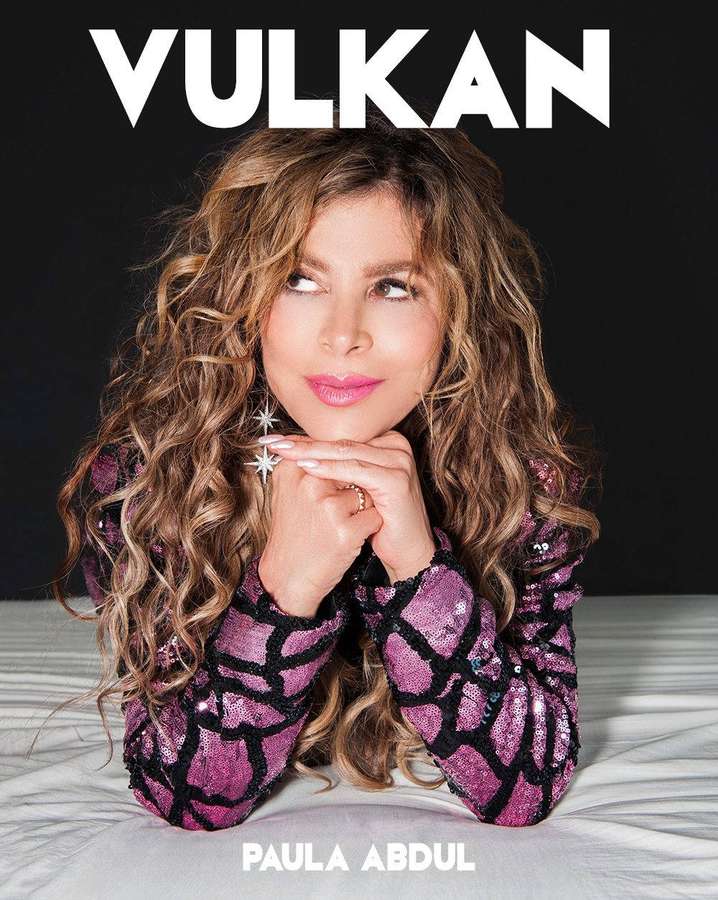 Paula Abdul in glitzerndem Outfit posiert auf Bett mit fettem Text — Paula Bilder