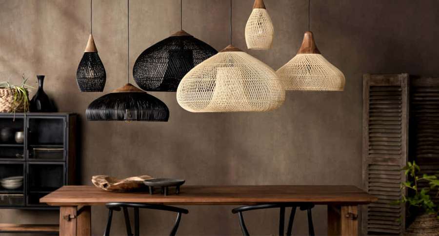 Woven pendant lights hang above a wooden dining table with black chairs in a rustic room. — Pendant Light Wallpaper