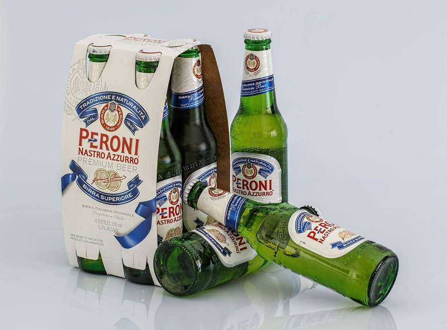Six-pack of Peroni Nastro Azzurro beer bottles with one lying down on white surface. — Peroni Beer Wallpaper