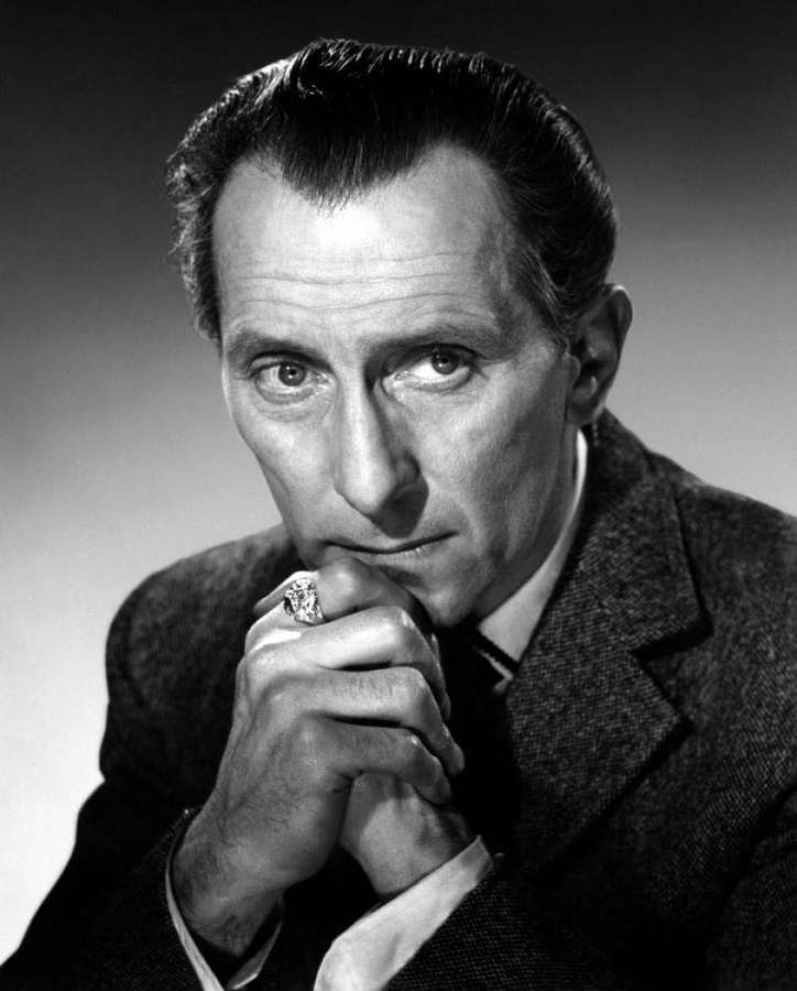 A man in a suit with a large ring looks directly at the camera in a studio portrait. — Peter Cushing Wallpaper