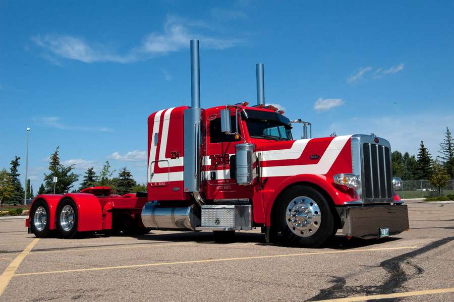 Red and white Peterbilt semi-truck parked on asphalt under blue sky — Peterbilt Wallpaper