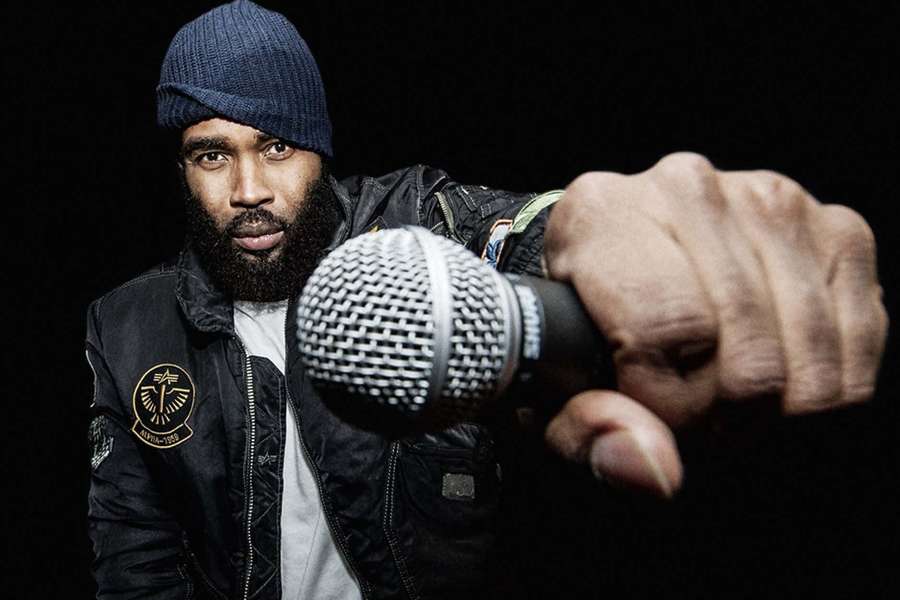 Mann mit Bart und Mütze hält Mikrofon im dunklen Studio. — Pharoahe Monch Wallpaper