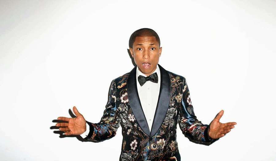 Man in floral tuxedo with open hands and surprised expression against white background. — Pharrell Williams Wallpaper