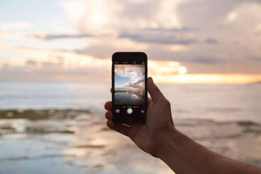 Mão segurando telefone tirando foto do pôr do sol na praia — Photography iPhone Papéis de Parede