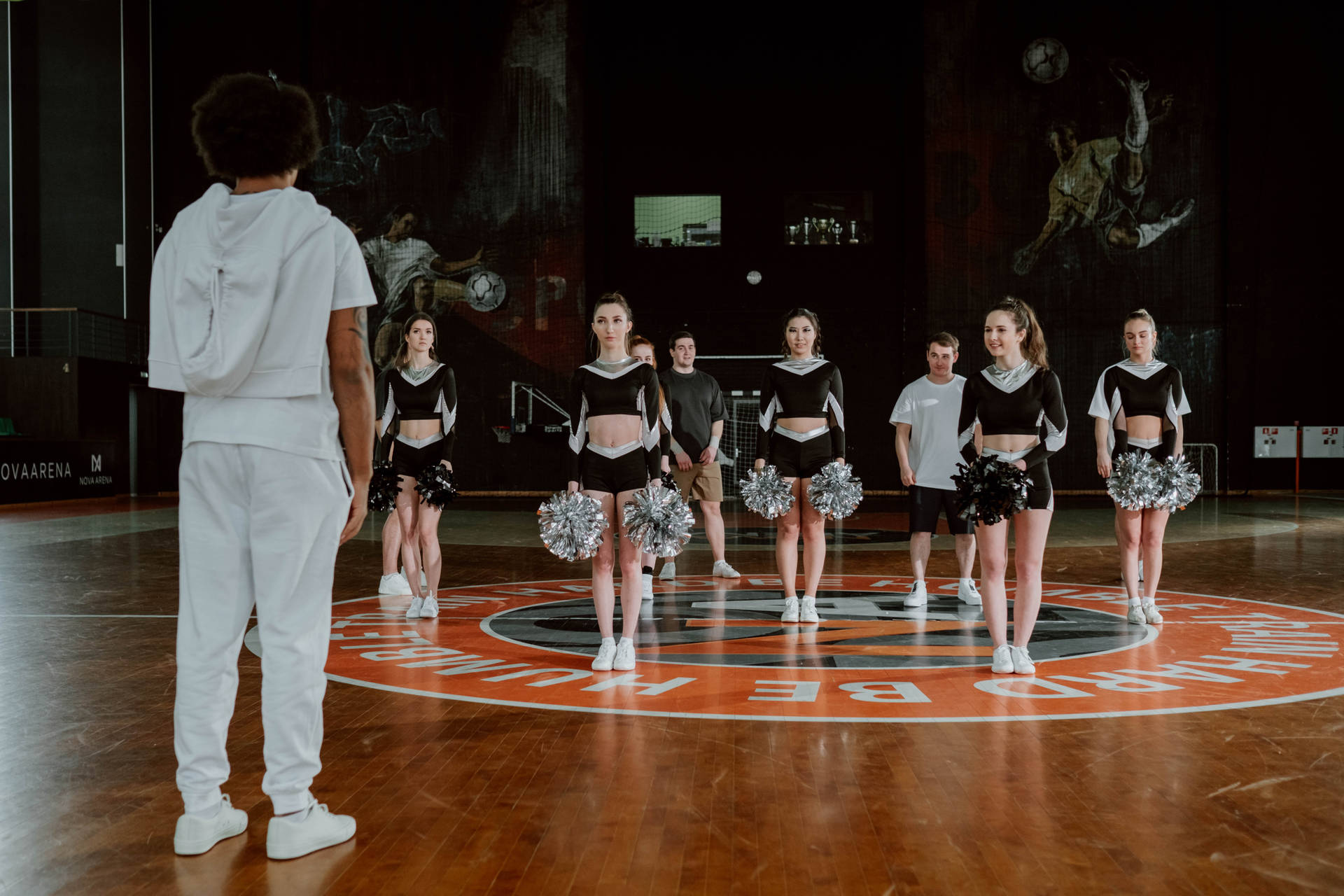 Tränare vänd mot cheerleaderlag på basketplan med pom-poms — Fysisk Bakgrundsbilder
