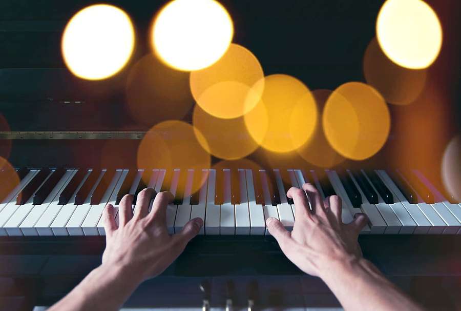 Hands playing piano with golden lights in background — Piano Background