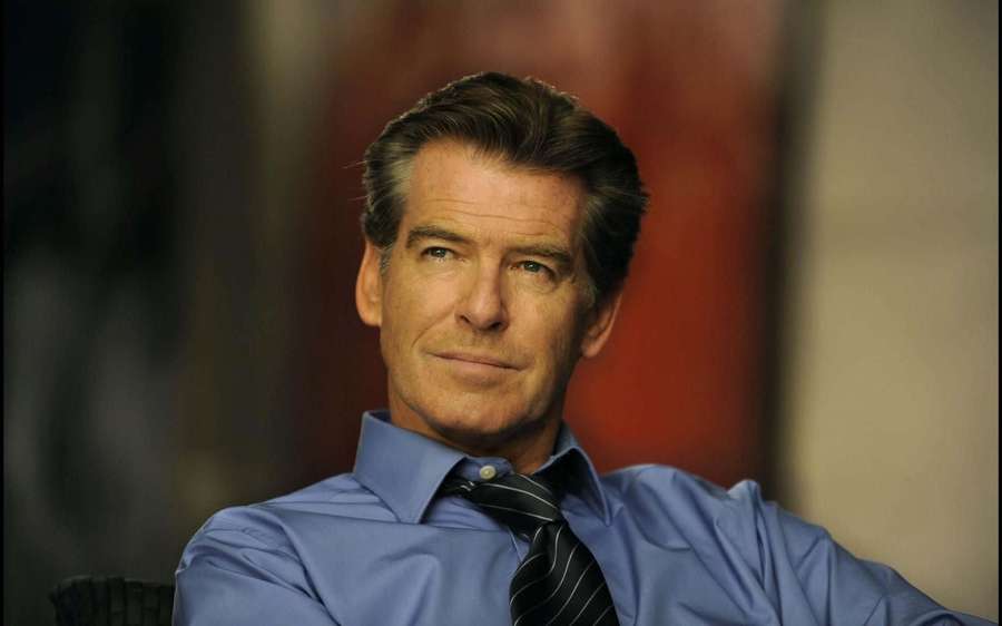 A man in a blue shirt and striped tie with a calm serious expression. — Pierce brosnan Wallpaper