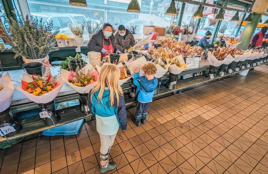 Zwei Kinder in Jacken schauen sich Blumensträuße an einem Marktstand an. — Pike Place Markt Wallpaper