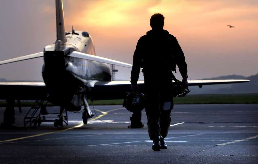 Silueta de un piloto caminando hacia un caza en una pista al atardecer. — Piloto Fondos de pantalla