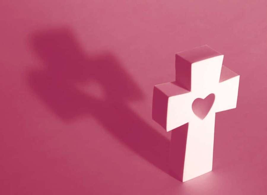 White cross with heart cutout casting shadow on pink surface — Pink Cross Wallpaper
