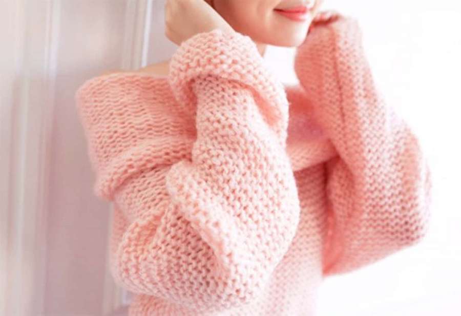 Person wearing a soft pink chunky knit sweater indoors. — Pink Sweater Wallpaper