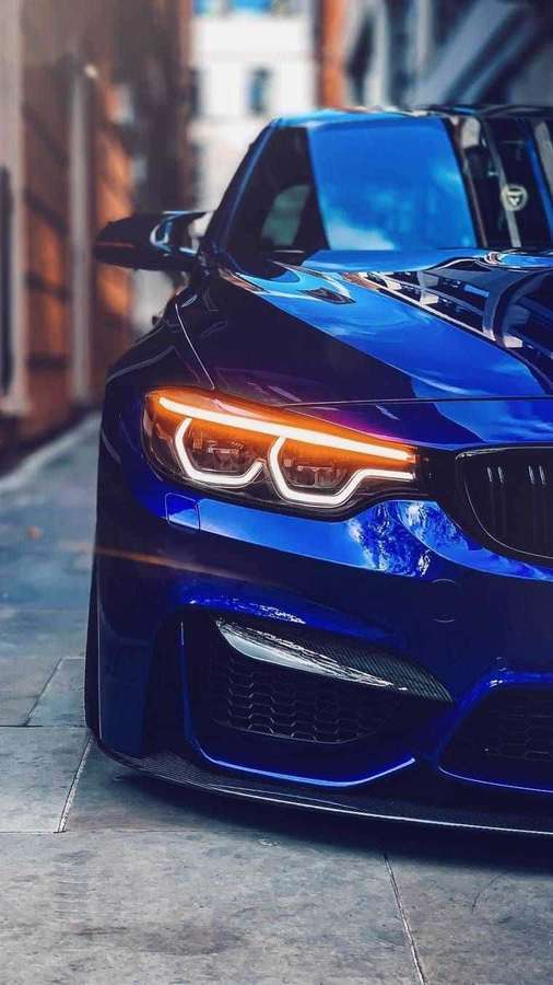 Blue sports car with illuminated headlights on city street at night. — Pixel 3 Bmw Background