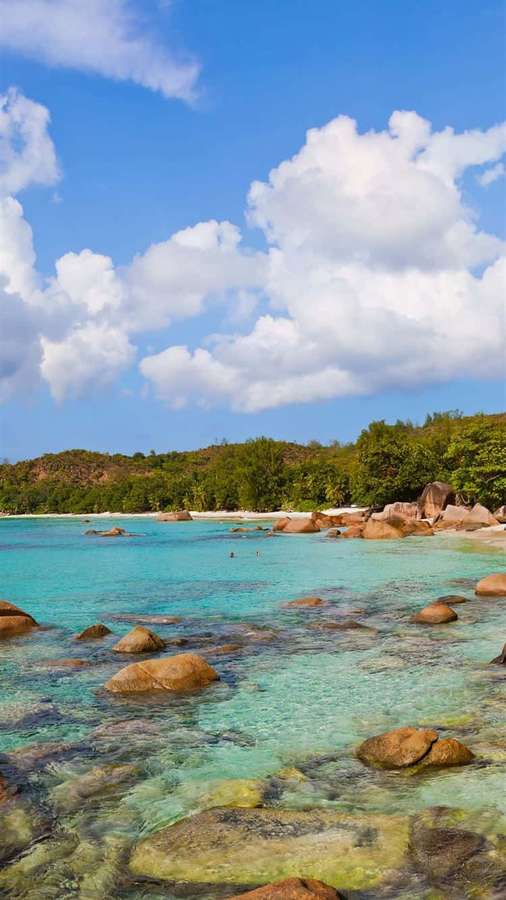 Playa tropical con agua turquesa y rocas de granito bajo un cielo azul con nubes. — Playa de Seychelles Fondos de pantalla