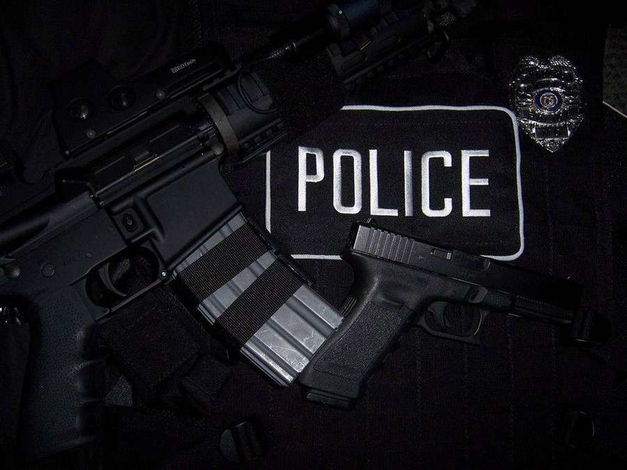 Pistola rifle e distintivo policial em um uniforme com patch policial. — Polícia Papéis de Parede