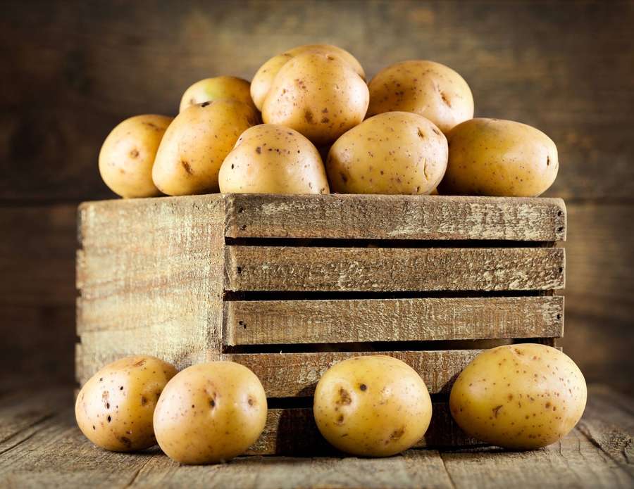 Fresh yellow potatoes in a wooden crate on a rustic wooden surface. — Potato Wallpaper