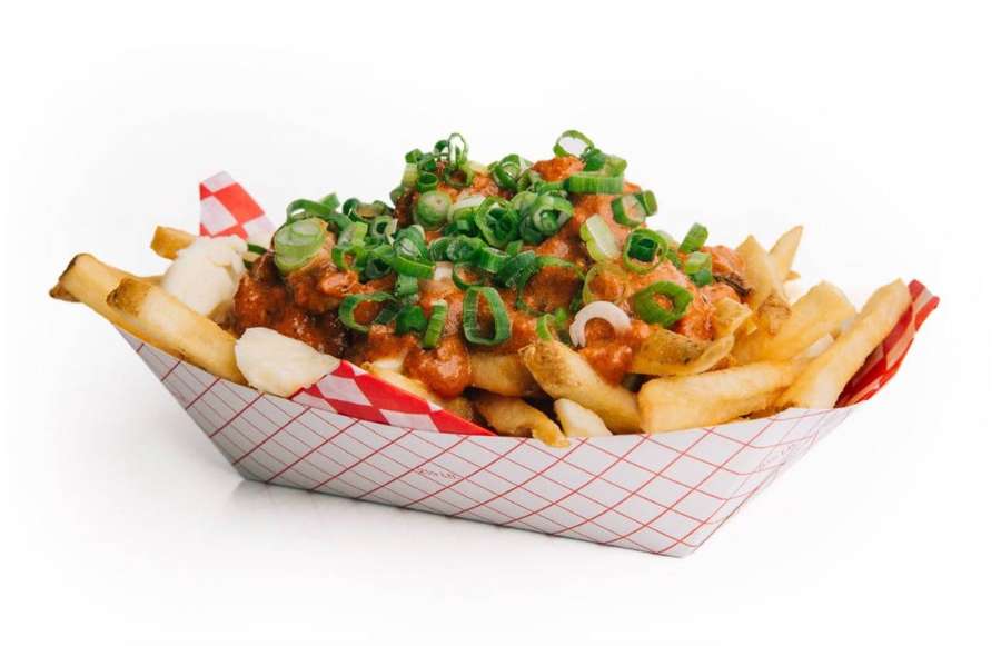 Chili-Käse-Pommes in einem rot-weiß karierten Papierboot, belegt mit Frühlingszwiebeln. — Poutine Bilder