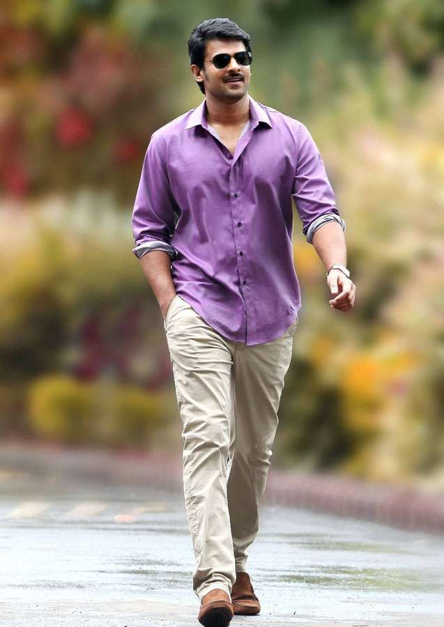 Man in purple shirt and beige pants walking on wet path with colorful foliage background. — Prabhas Mirchi Background