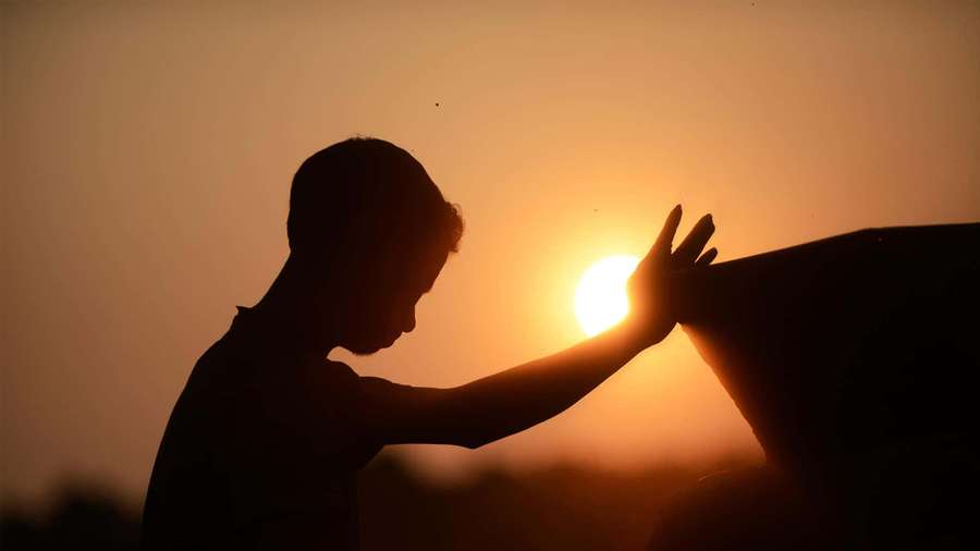 Person reaching toward setting sun in silhouette against orange sky — Prayer Background