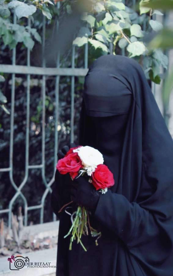 Pessoa em niqab preto segurando rosas vermelhas e brancas no jardim. — Preto elegante Papéis de Parede