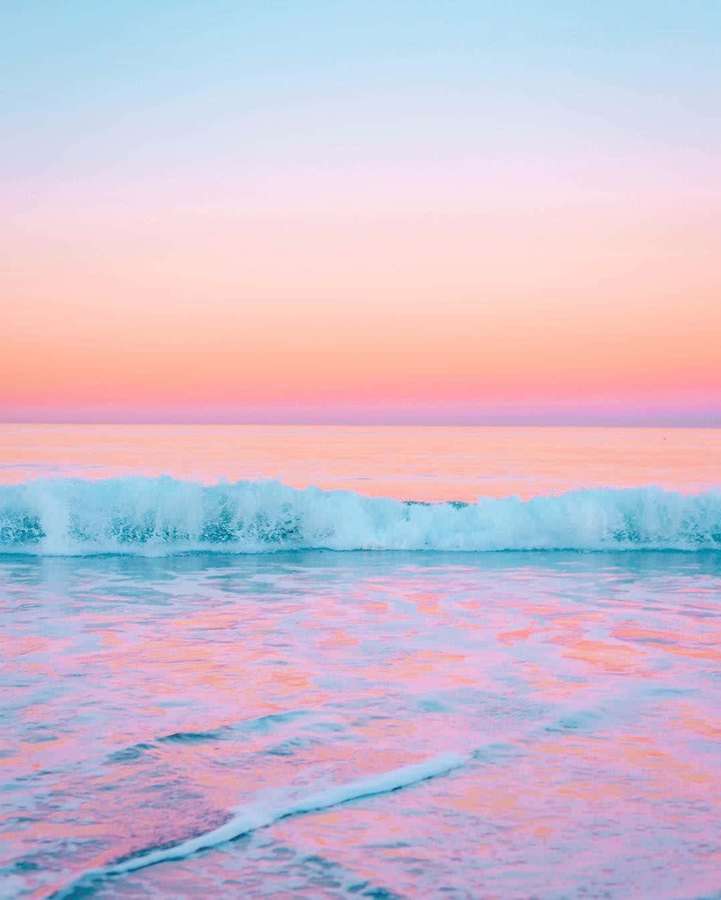 Pastel sunset over ocean with gentle waves rolling in. — Pretty Ocean Wallpaper