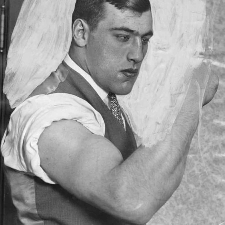 A strong man lifting a heavy sack over his shoulder in a vintage black and white photo. — Primo Carnera Wallpaper