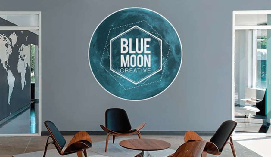 Modern office lounge with blue moon logo on wall and wooden chairs. — Professional Background