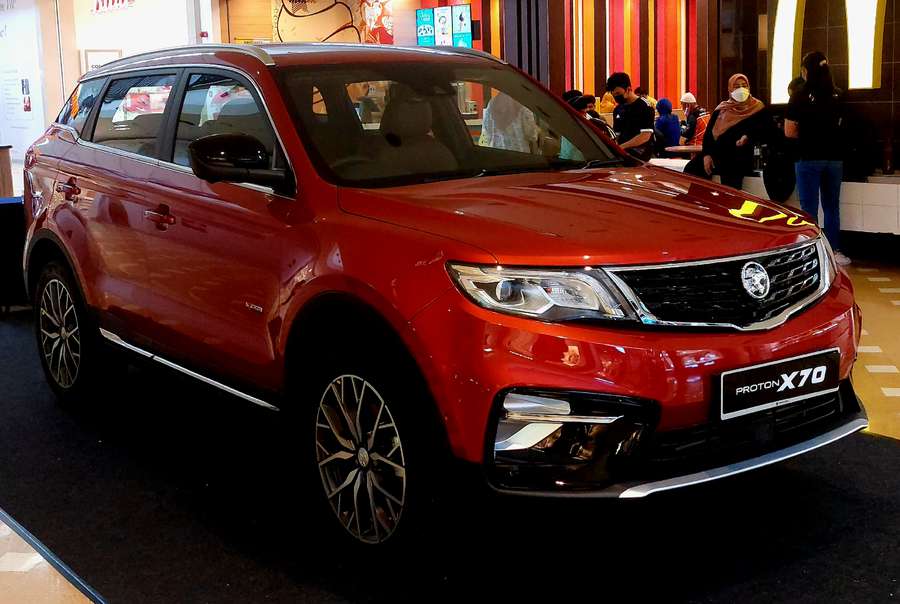 Red Proton X70 SUV on display with people nearby. — Proton X70 Wallpaper