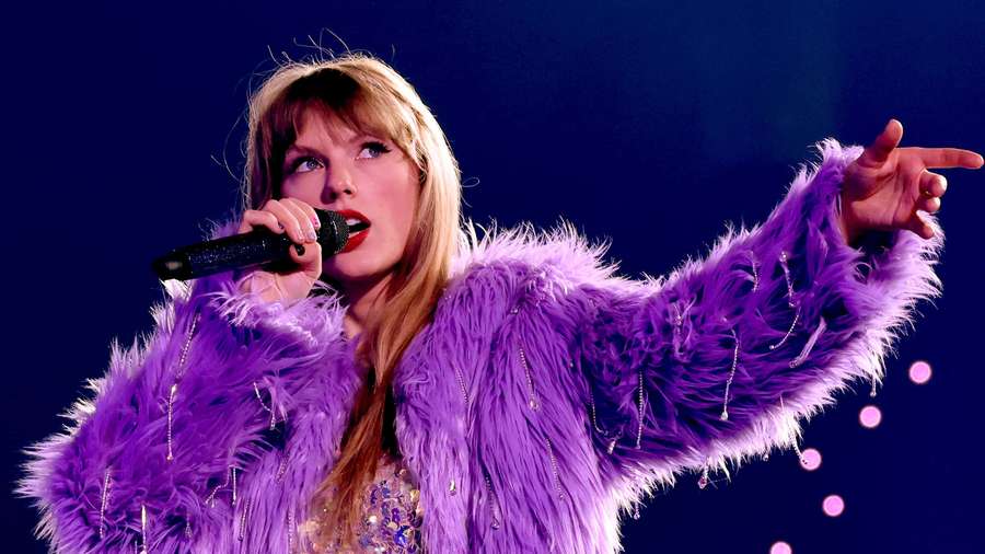 Taylor Swift singing in a purple fur coat on a concert stage. — Purple Jacket Wallpaper