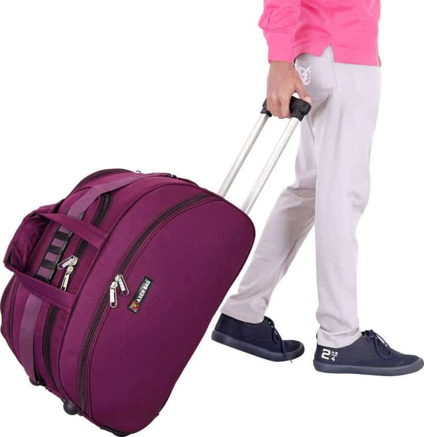 Person pulling a purple rolling duffel bag with silver zippers and black wheels. — Purple Suitcase Wallpaper