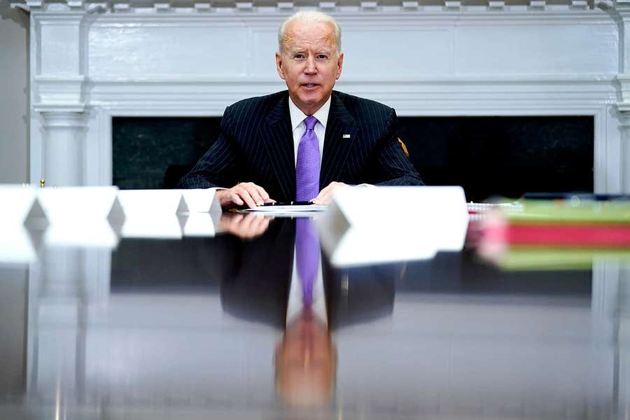 President Biden seated at a desk in an official office with a white fireplace. — Purple Tie Wallpaper