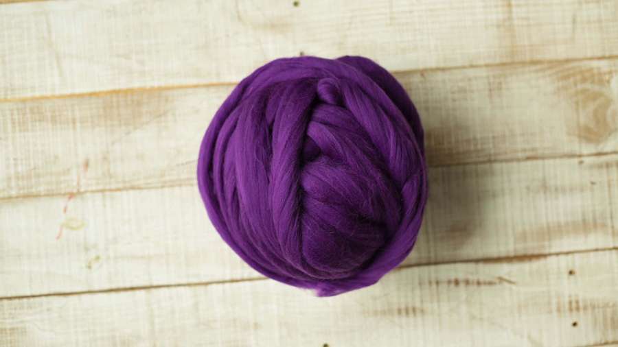 A ball of purple yarn on a wooden surface. — Purple Wool Wallpaper