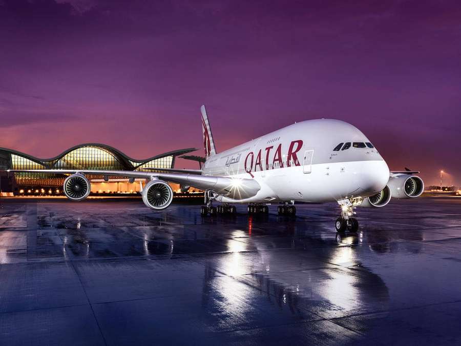 Qatar Airways A380 airplane on wet tarmac at night with glowing terminal behind. — Qatar Airways Wallpaper