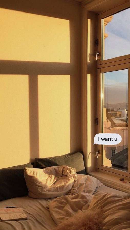 A luz do sol entra por uma janela projetando sombras em uma cama com travesseiros e um caderno — Quarto estético Papéis de Parede