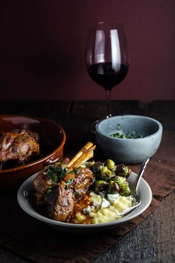 Piernas de cordero con coles de Bruselas y puré de papas con vino tinto en mesa de madera. — Queso Azul Fondos de pantalla