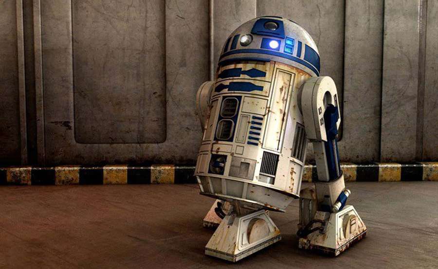 R2-D2 droid with rust and wear in a metal warehouse setting. — R2d2 Wallpaper