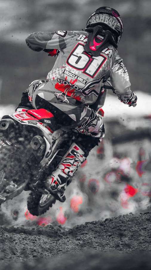 Motocross rider airborne over dirt track with red accents in grayscale background. — Racing Wallpaper
