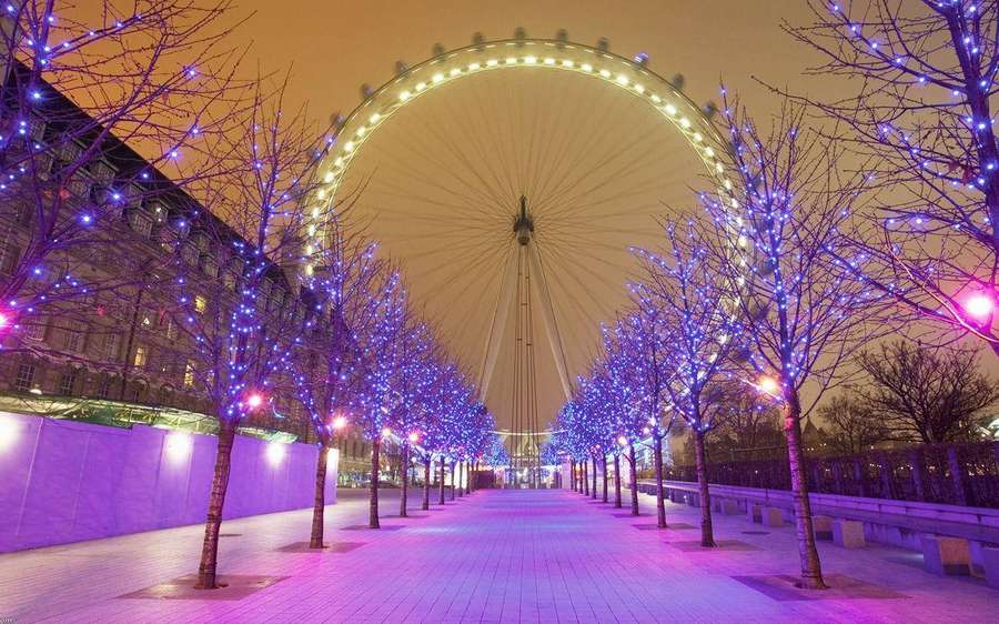Ein nächtlicher Gehweg mit blau beleuchteten Bäumen, die zum London Eye führen. — Rad Wallpaper