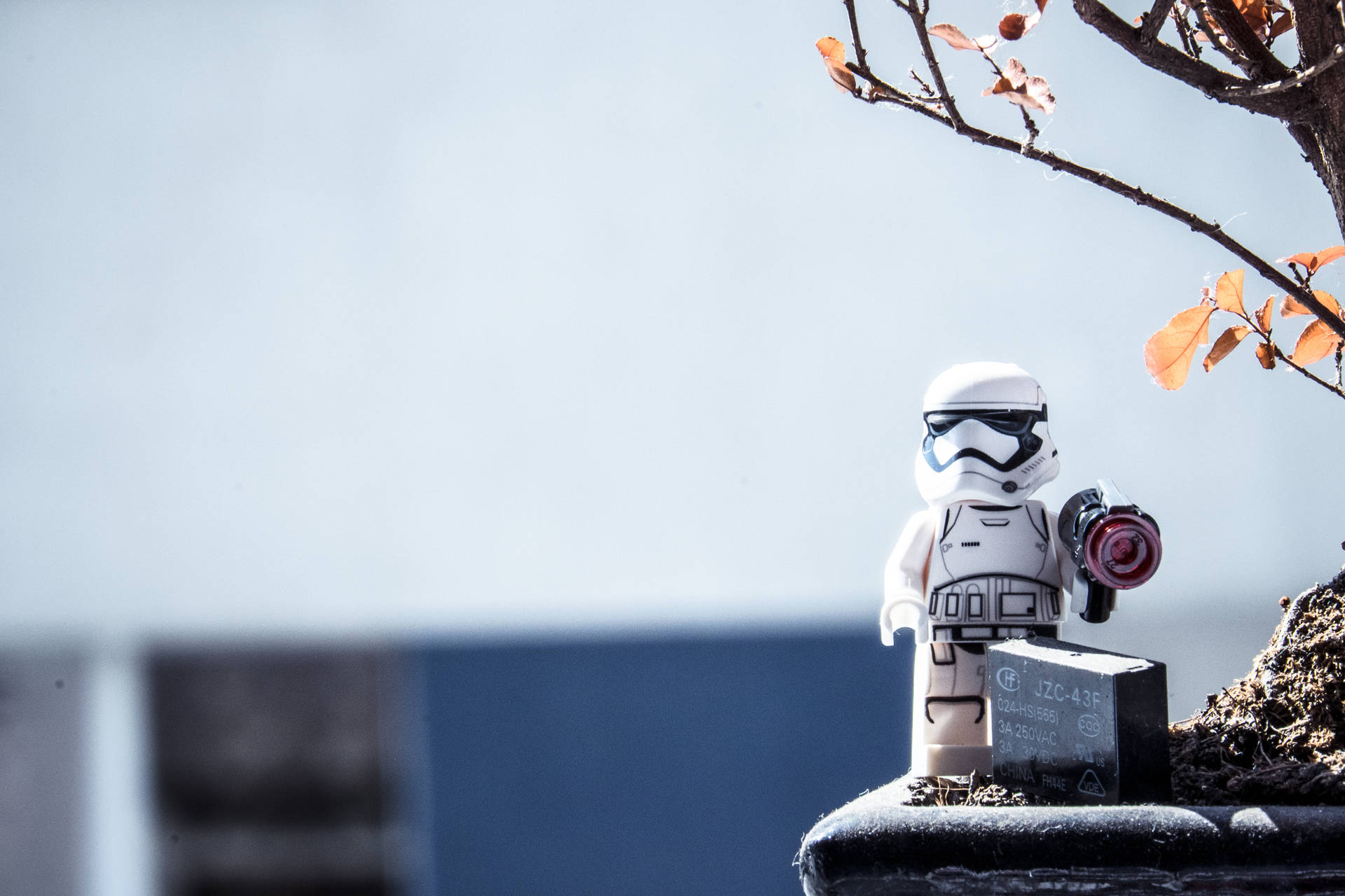 En LEGO-stormtrooper-figur placerad på en avsats med höstlöv och en trädgren. — Raid bakgrund Bakgrundsbilder