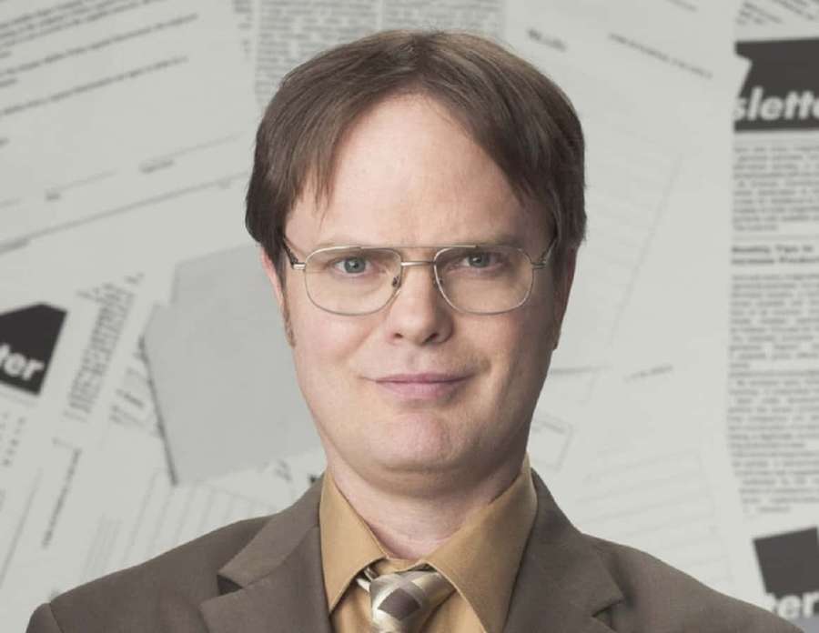 Man in glasses and suit smiling in office setting with papers behind him — Rainn wilson Wallpaper