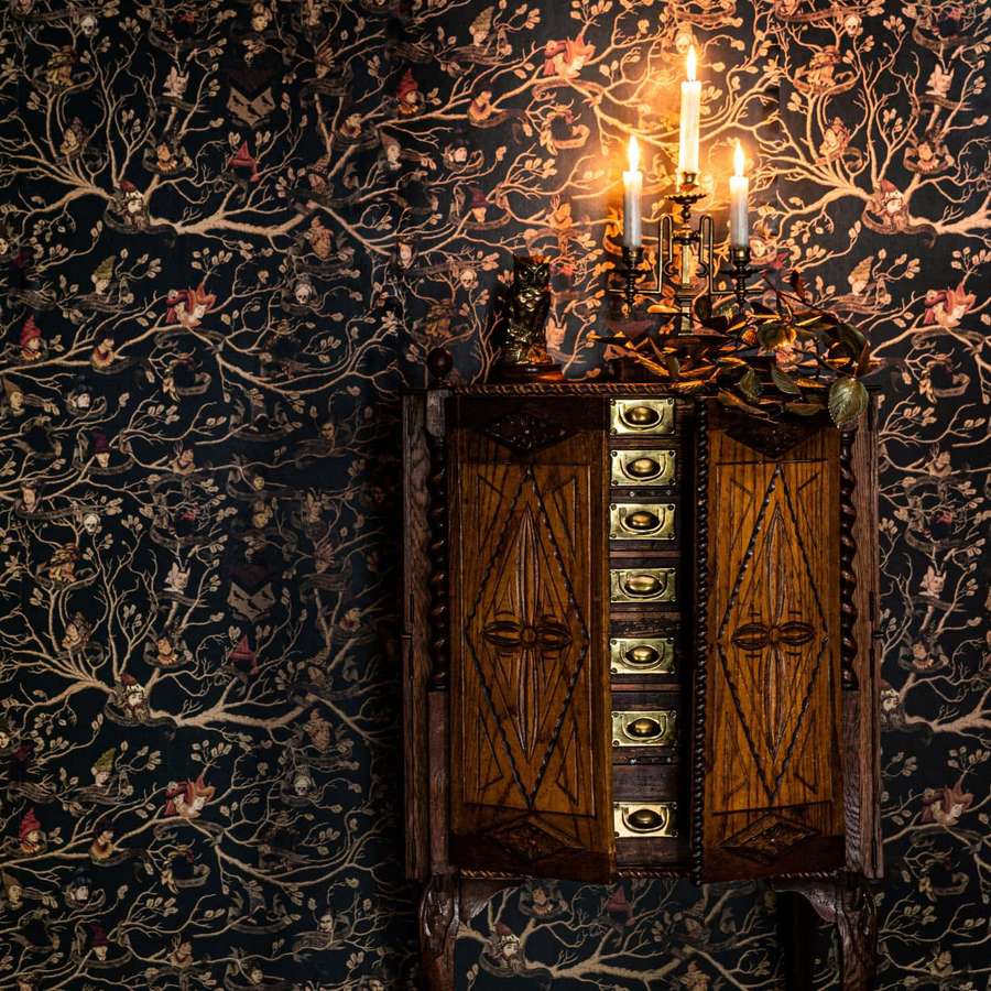 Un armario de madera vintage con tiradores de latón contra un papel tapiz oscuro y místico con ramas de árboles y pequeñas figuras. — Rama Fondos de pantalla