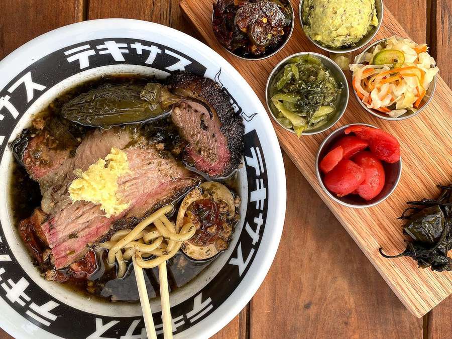 Eine Schüssel Rindfleisch-Ramen mit Stäbchen und Beilagen auf einem Holztisch. — Ramen Bilder