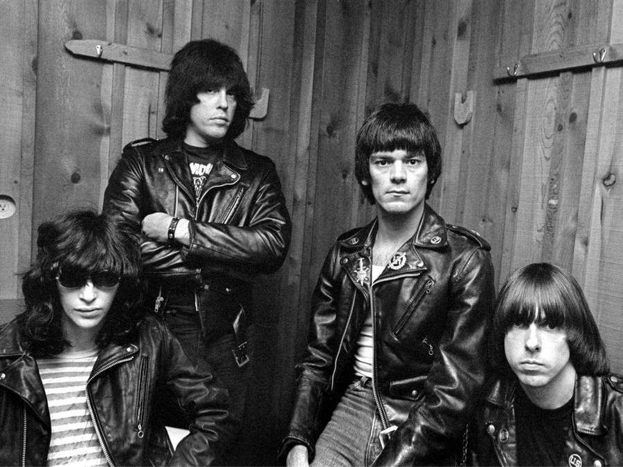 Four punk rockers in leather jackets stare intensely at the camera. — Ramones Wallpaper